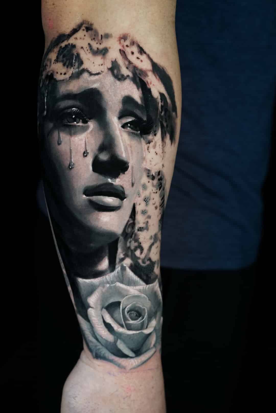 Jose Carlos 6 A black and white tattoo on an arm depicts a crying woman's face with a rose below it.