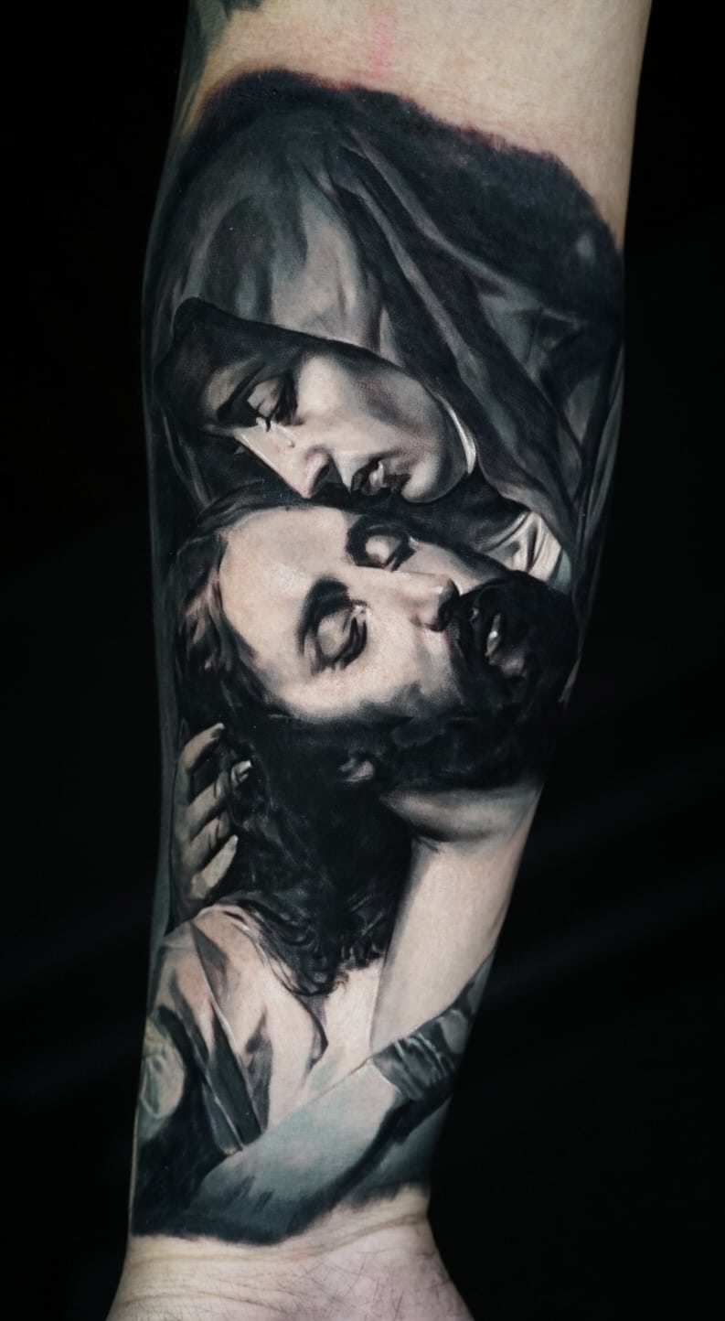 Jose Carlos 16 A black and white tattoo on an arm depicts a woman in a veil cradling a man's head.