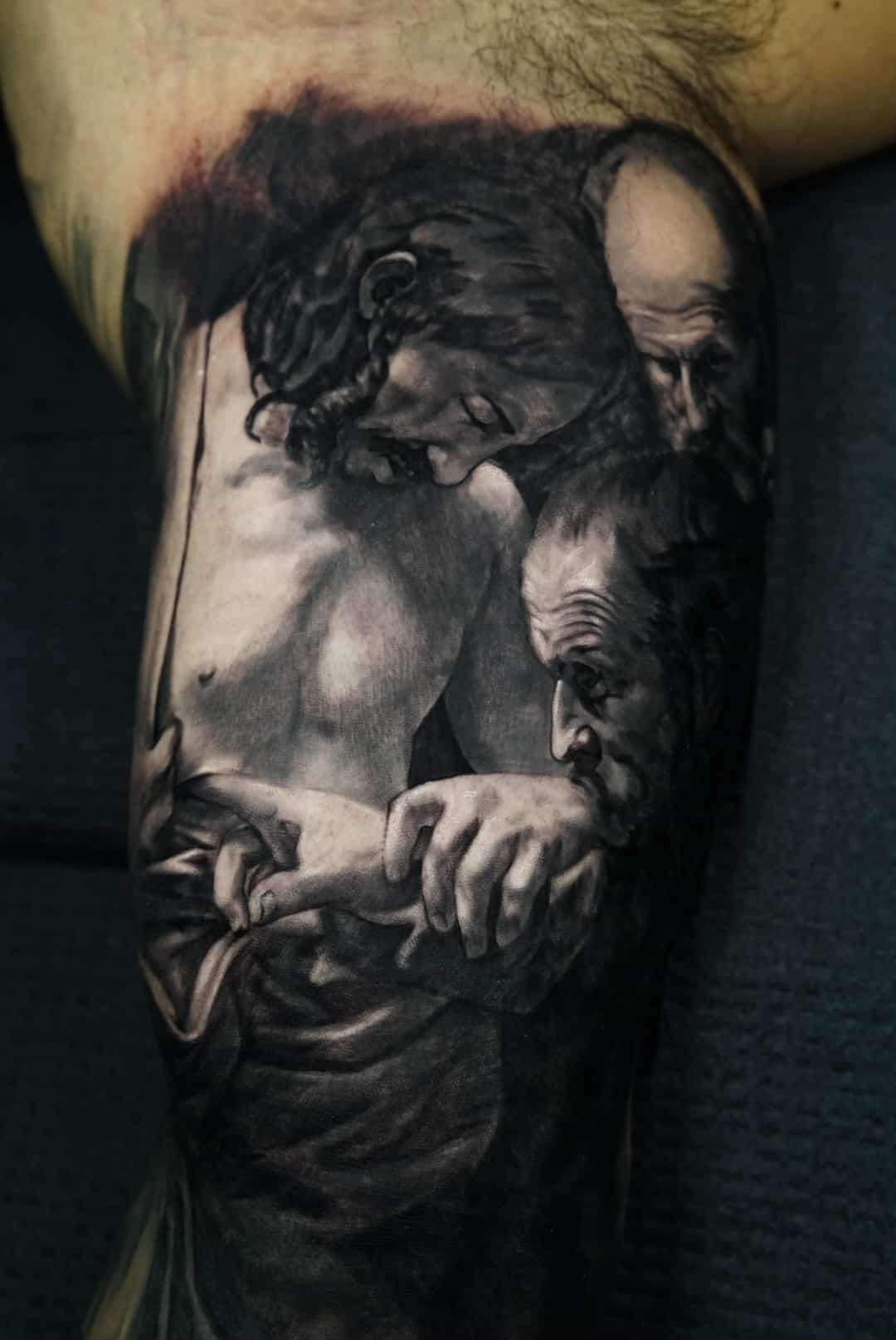 Jose Carlos 20 A black and white tattoo on an arm depicts three men, two of whom are holding hands.