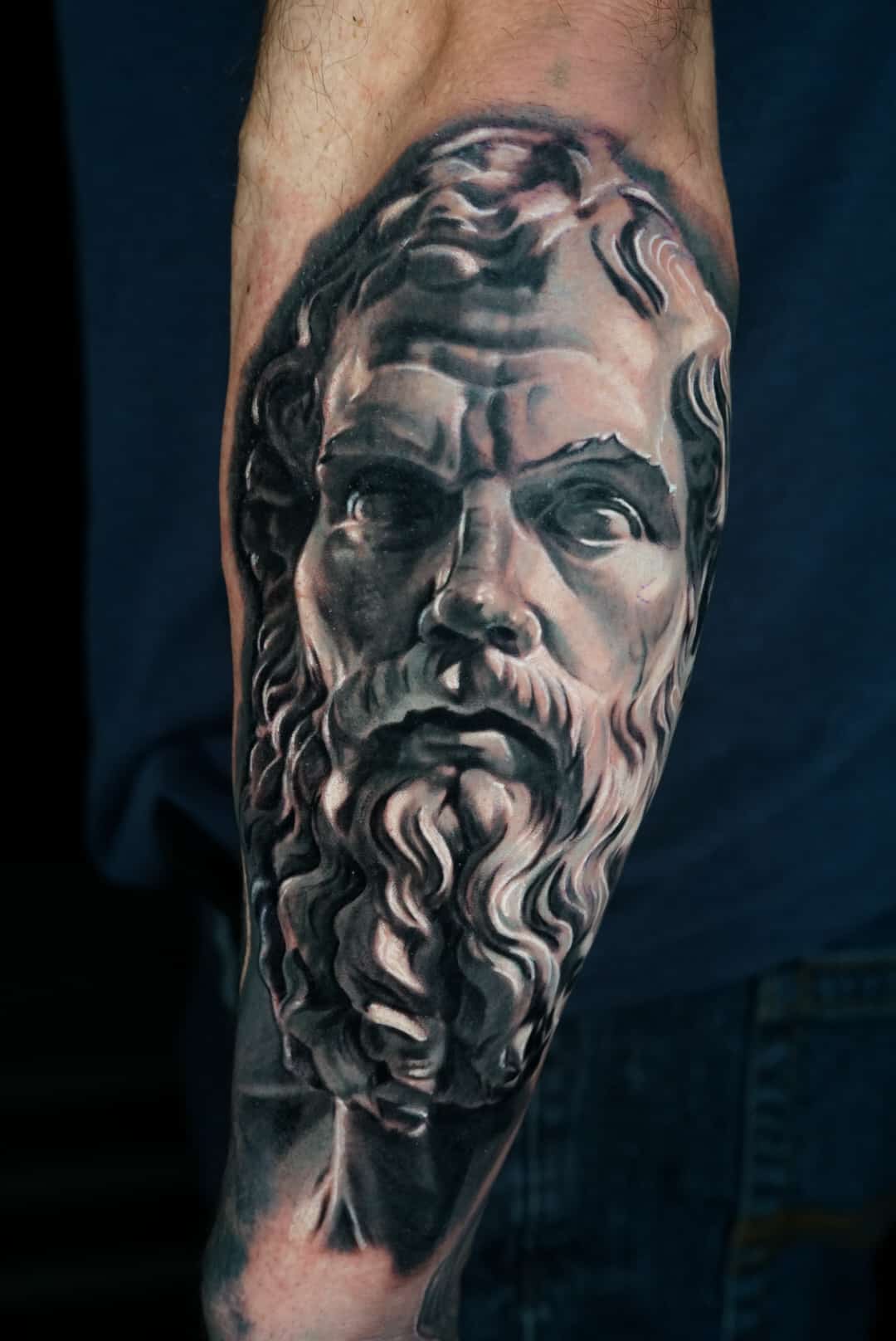 Jose Carlos 24 A detailed black and white tattoo of a classical bust with a beard and wavy hair on a person's arm.