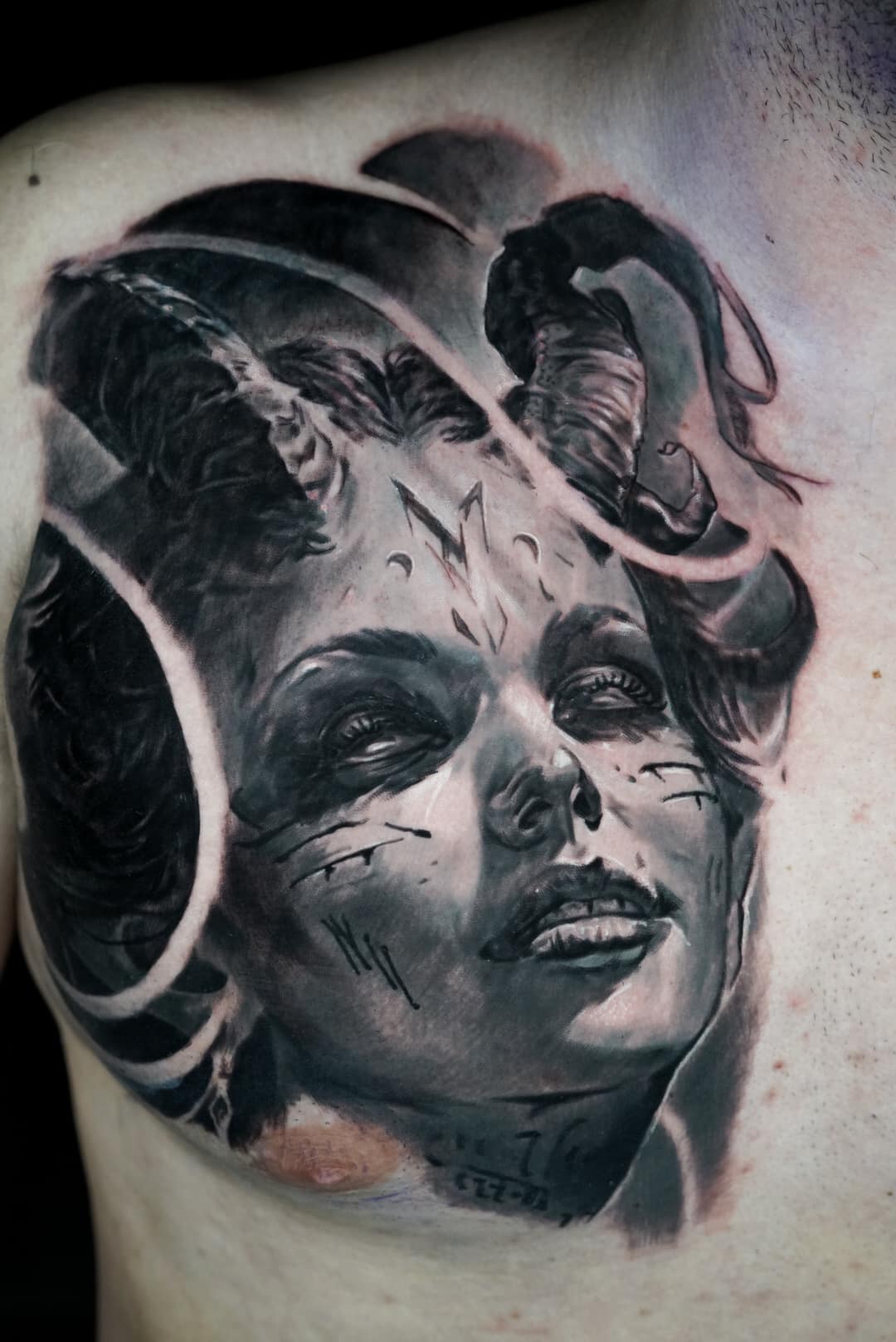 Jose Carlos 30 A black and gray tattoo of a horned woman's face with closed eyes and a slight smile on a man's chest.