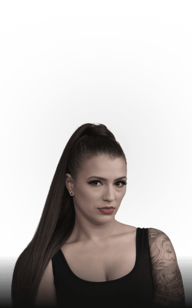 A woman with long dark hair in a high ponytail and a black tank top looks at the viewer.