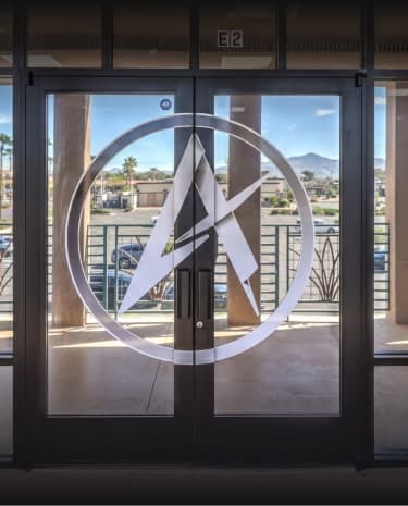 Glass double doors with a white circular logo featuring abstract letters and "E2" above the frame.
