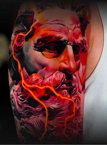 A vibrant tattoo of a statue's head with a beard, in shades of red and black, with orange lightning bolts.