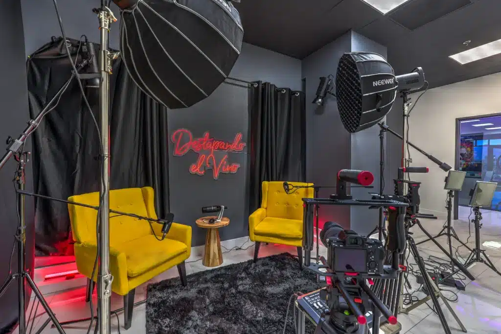 A recording studio with two yellow armchairs, microphones, cameras, and "Destapando el Vivo" in red neon.